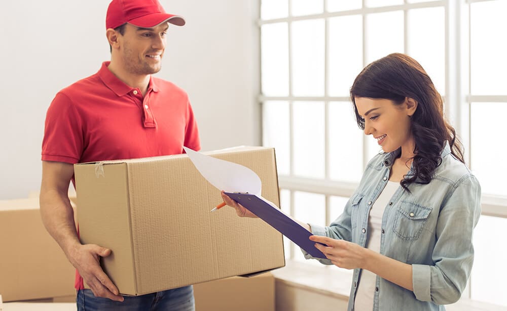 A woman is handing her package to a delivery man.