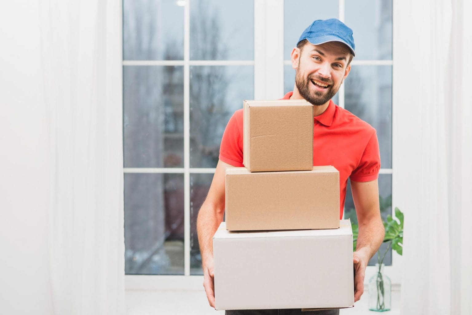 A man holding boxes in front of a window.